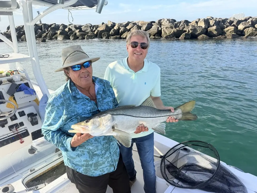 Two anglers with a snook by the Ponce Inlet jetties