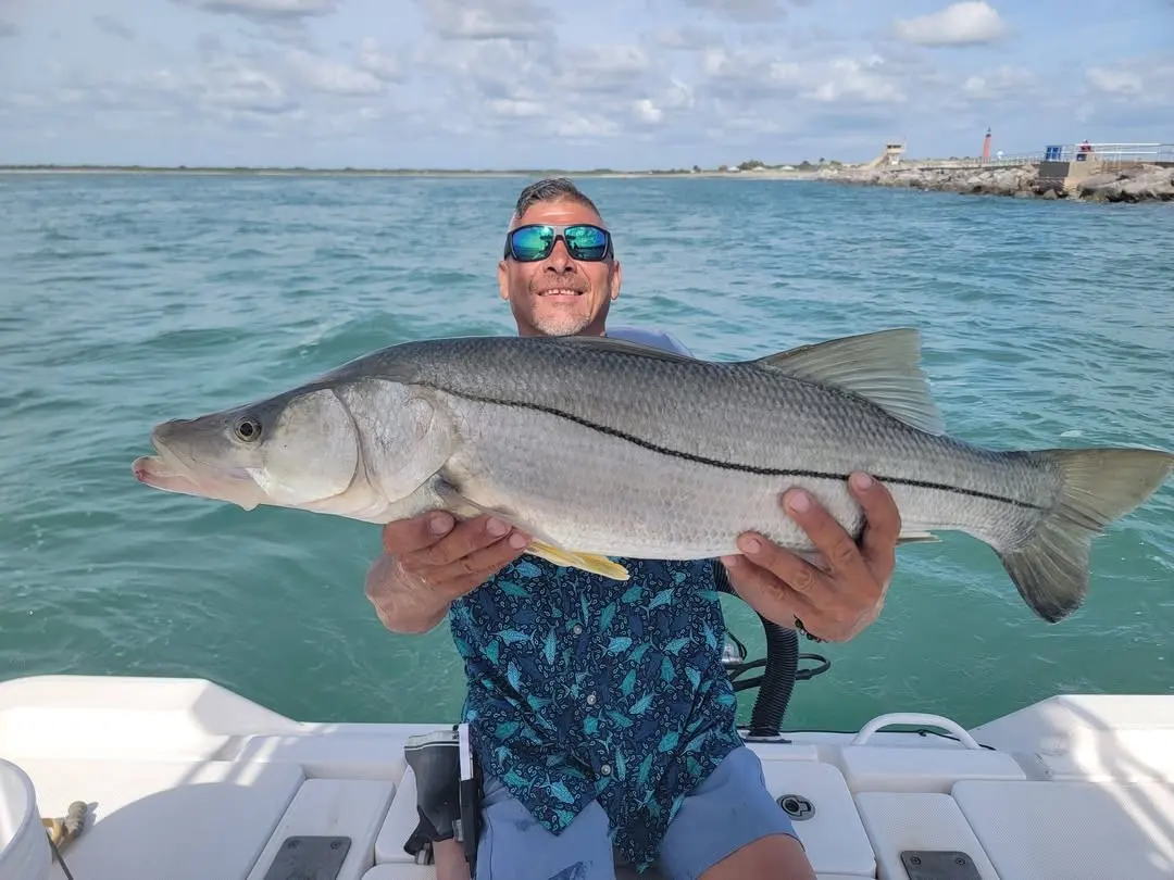 Angler holding a big snook over turquoise water