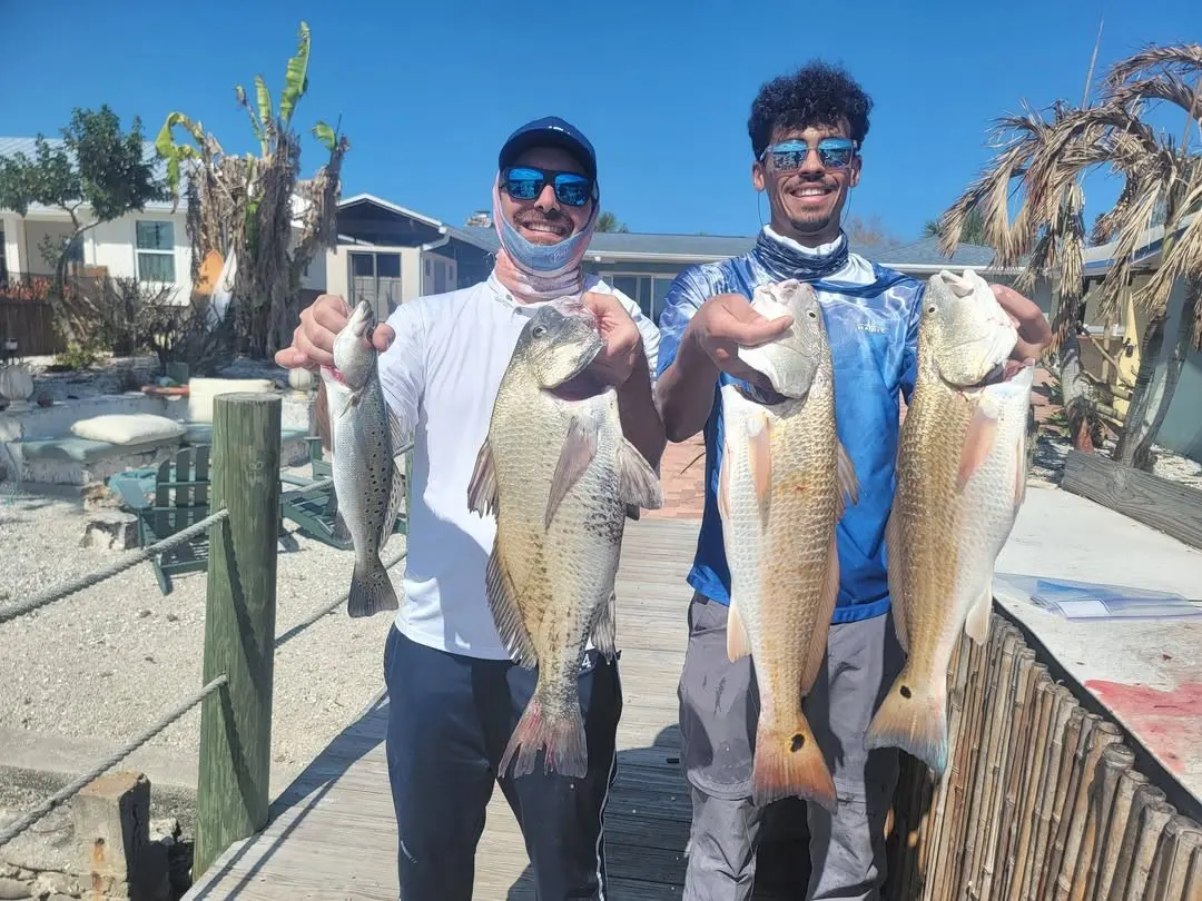 Three anglers with redfish on the dock