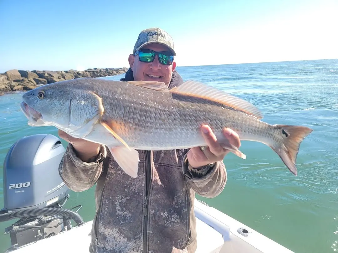 Angler with a bull redfish next to the EdgeWater