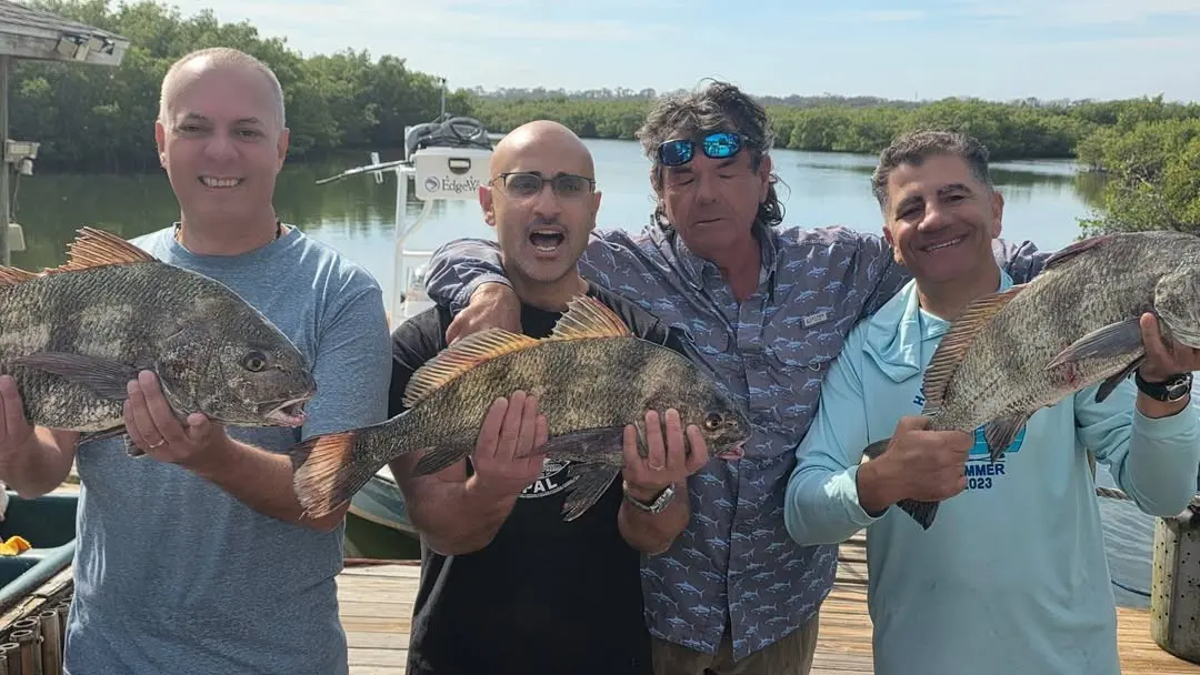 Three anglers with snook and redfish on the dock