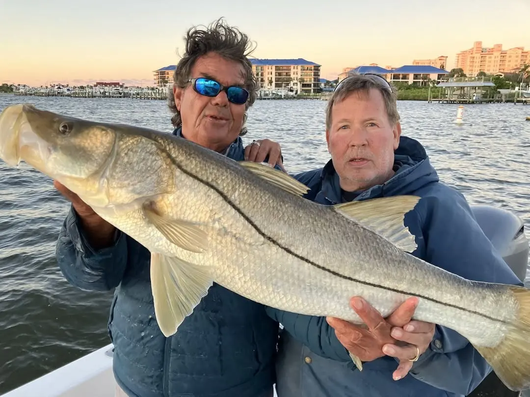 Two anglers with a snook at sunrise