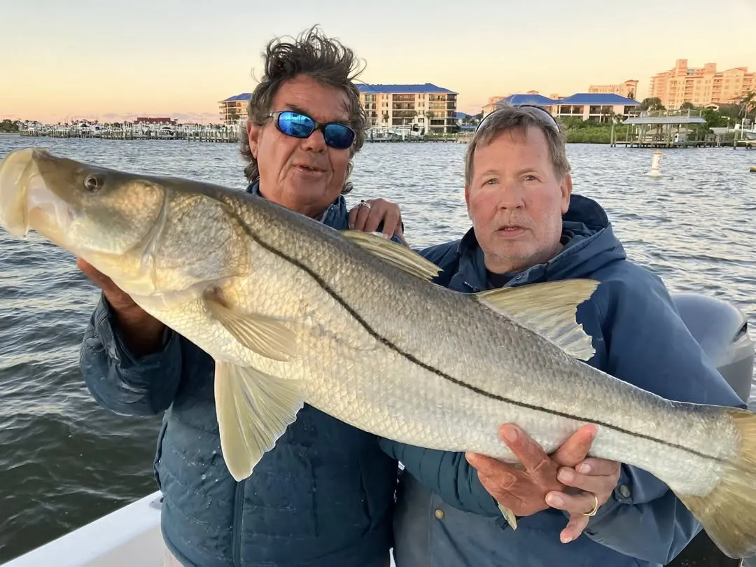 Two anglers with a big snook at sunset