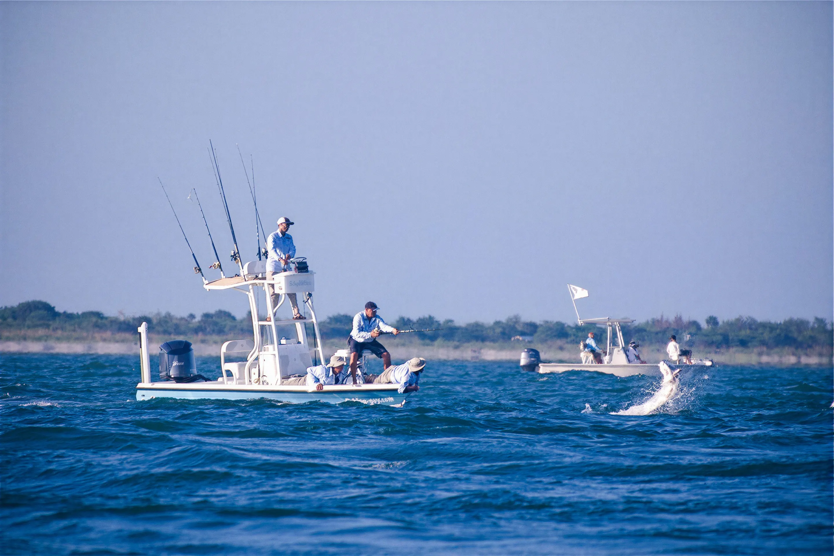 A tarpon jumping next to a center console boat while anglers fight it near Ponce Inlet
